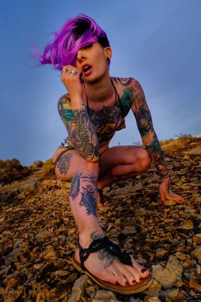 Hot alternative babe called Miss Bat lustfully poses in the rocky field showing us her body with tiny breasts and full of tattoos in Crazy Babe set Wild in the Rocky Valley
